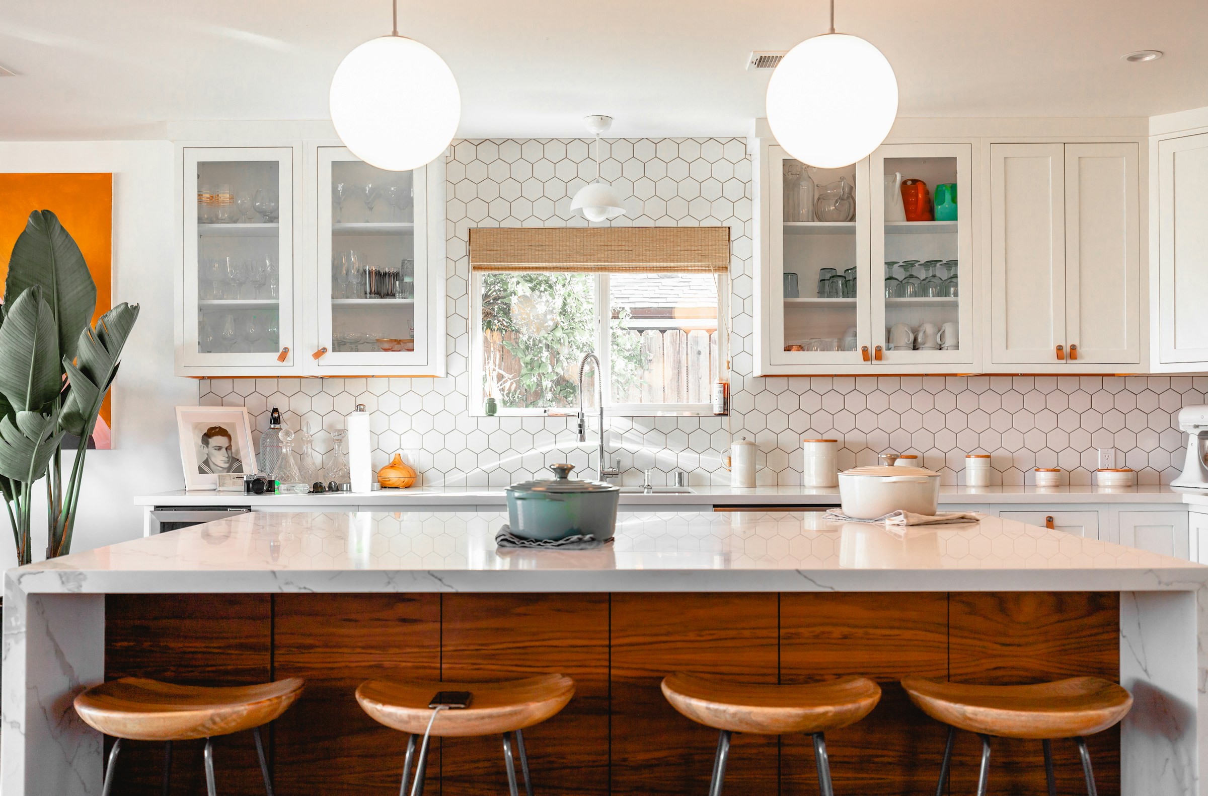 Light-filled kitchen with white cabinetry, a richly grained island and wood stools